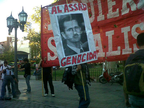 Pancartas contra el dictador genocida de Siria Bashar Al Assad en el acto en Córdoba, Argentina