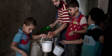 Varios niños recogen la comida dada por una organización benéfica en el barrio de Bustan al-Qaser. J.M. LÓPEZ