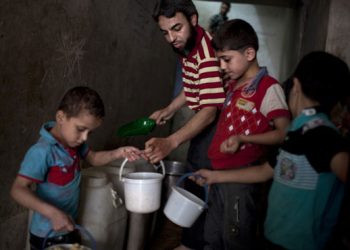 Varios niños recogen la comida dada por una organización benéfica en el barrio de Bustan al-Qaser. J.M. LÓPEZ